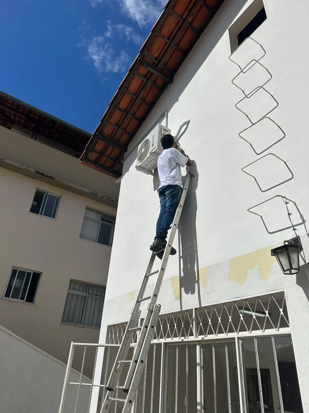 Técnico da MK Climatização instalando ar-condicionado em fachada de prédio na Grande BH